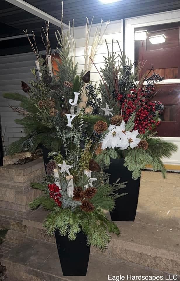 Festive winter planters with greenery, pinecones, red berries, and 'JOY' decorations.