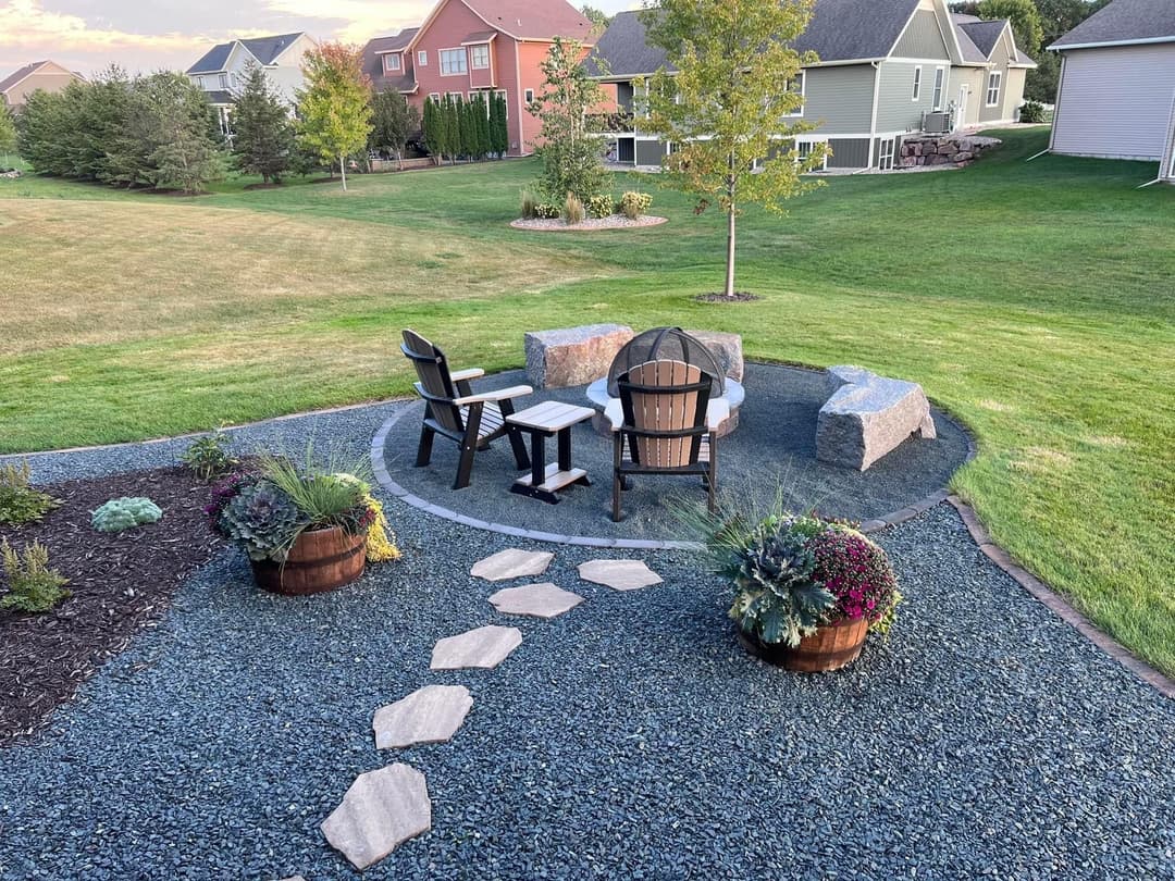 Cozy outdoor seating area with chairs, stone pathways, and landscaped garden.