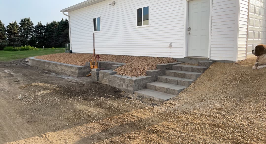 Newly constructed exterior steps and landscaping with gravel beside a white house.
