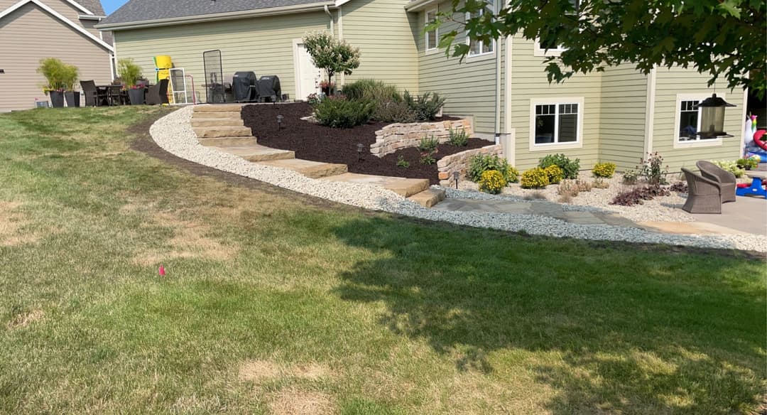 Landscaped backyard with stone steps, flower beds, and a cozy seating area.