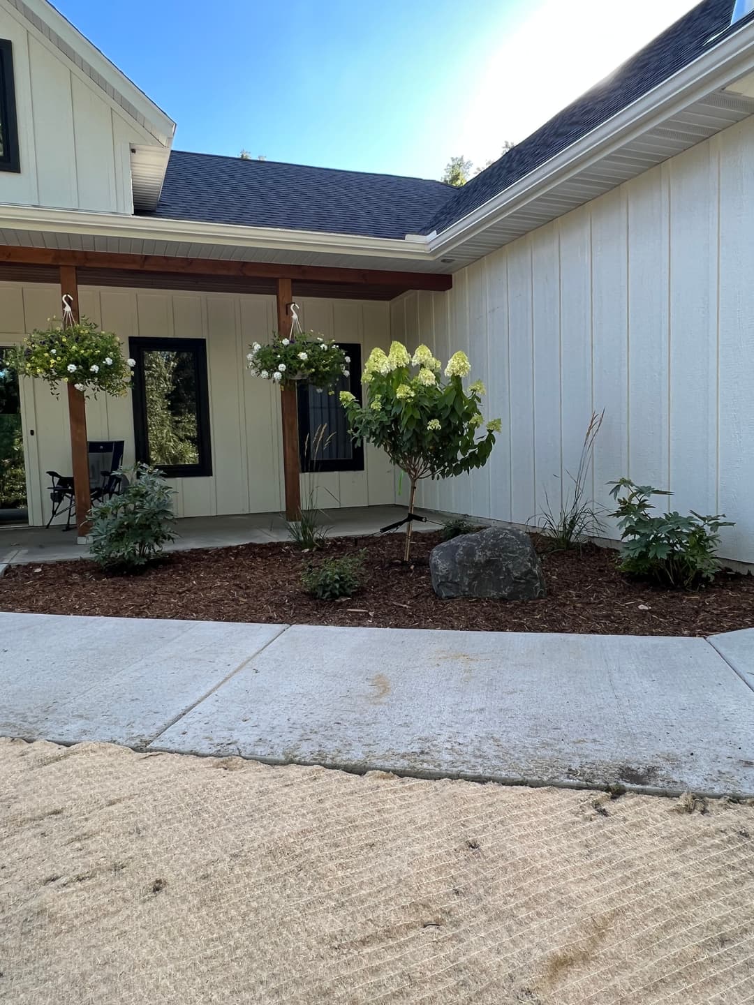 Home exterior with planters, hydrangea tree, and landscaped garden area.