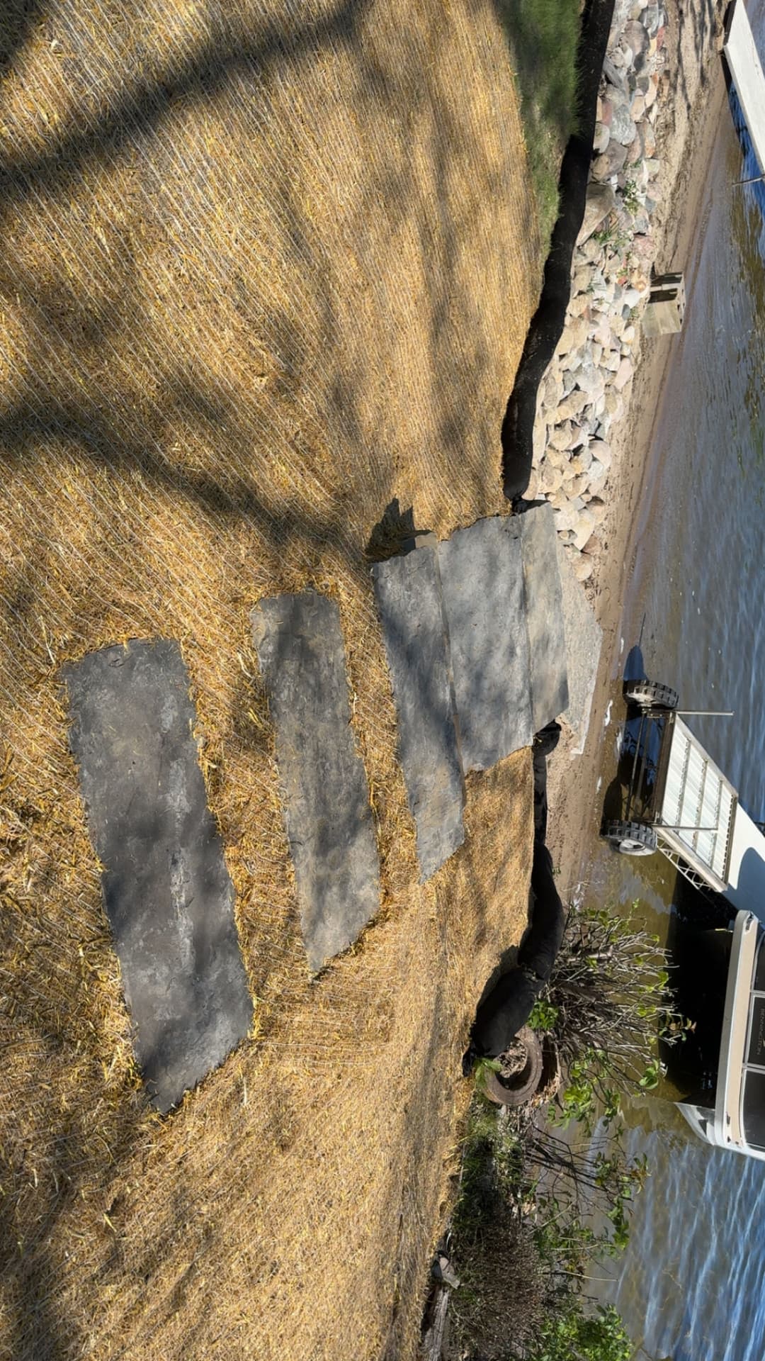 Stone pathway leading to water on a riverbank, surrounded by grass and rocks.